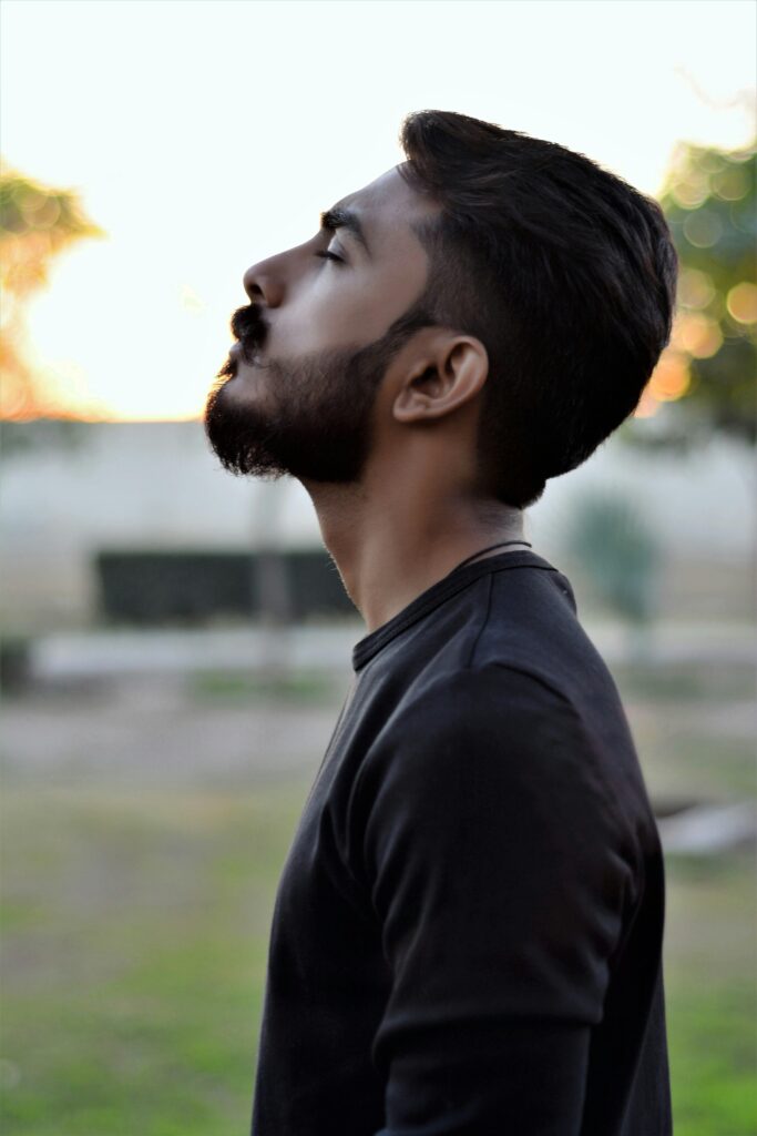 pexels-photo-761115-761115 Side view portrait of a bearded man gazing upwards in an outdoor setting with blurred background.